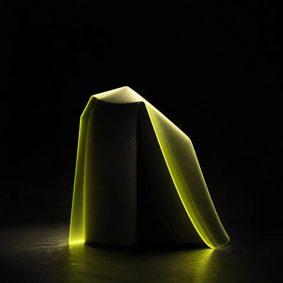 Dark sculptural monolith in a luminous material study.
